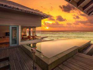 a house on the beach with a sunset at Raffles Maldives Meradhoo in Gaafu Alifu Atoll