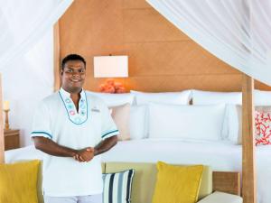 a man standing in front of a bed at Raffles Maldives Meradhoo in Gaafu Alifu Atoll