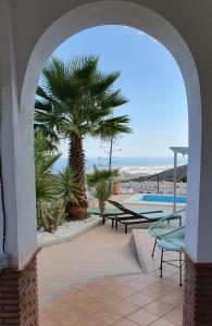 un arco con una palmera y una piscina en CASA JAN with pool, mountain and sea views., en Enix
