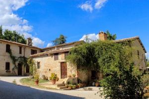 an old stone building with a tree in front of it at Agriturismo Camiano Piccolo in Montefalco