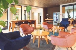 a lobby with chairs and tables and a bar at Tailormade Hotel STANS SÜD in Stans