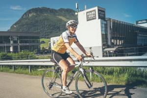 Un uomo che va in bicicletta lungo la strada di Tailormade Hotel STANS SÜD a Stans