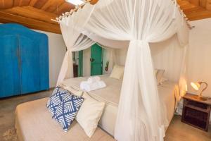 Un dormitorio con una cama con dosel y cortinas blancas. en Casa do Pescador, en Praia do Espelho 39 fotos más