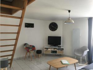 ein Wohnzimmer mit einem TV und einer Uhr an der Wand in der Unterkunft L Ecrin, duplex classé 2 étoiles, au cœur de Villandry in Villandry
