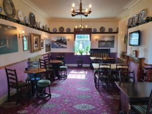 ゴースランドにあるThe Goathland Hotelの紫の壁の部屋にテーブルと椅子が備わるレストラン