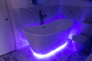 a white bath tub sitting under a blue light at Karma Sanctum Soho Hotel in London