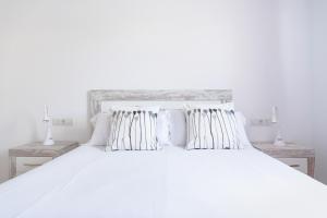 a white bedroom with a large white bed with pillows at Casco Antiguo 1 Piscina, Terraza y Parking by Vero in Altea