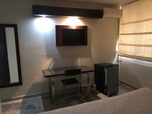 a room with a desk and a television on a wall at Hotel Mar Azul by Croma in Santa Marta