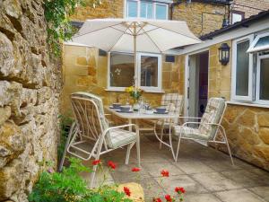 a table and chairs with an umbrella on a patio at Woodbine Cottage in Bourton on the Water