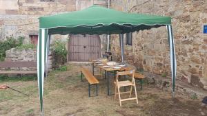 uma mesa e cadeiras debaixo de um guarda-sol verde em Casa en Orbó-Brañosera em Orbó