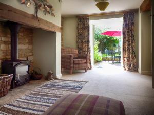 a living room with a fireplace and a chair and an umbrella at Greystones Cottage in Bourton on the Water