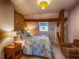 a bedroom with a bed and a chair in it at Greystones Cottage in Bourton on the Water