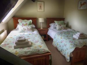 a bedroom with two beds with towels on them at Greystones Cottage in Bourton on the Water