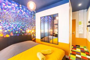 a bedroom with a yellow bed and a colorful wall at SMILE APPARTS - Appartements - Au coeur de Lorient - Au calme - Tout Confort in Lorient