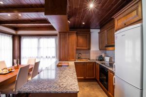 cocina con armarios de madera y nevera blanca en MONTOLIU de Alma de Nieve, en Baqueira Beret