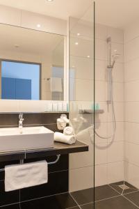ein Bad mit einem Waschbecken und einer Dusche in der Unterkunft Hotel Adler Münster in Münster