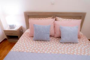 Una cama con almohadas rosas y azules. en Myrtle, city center renovated apartment, en Atenas