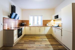 una cucina con armadietti bianchi e pavimenti in legno di Apartmán LYRA 