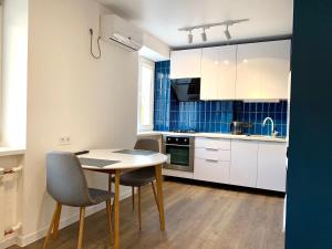 uma cozinha com armários brancos e uma mesa e cadeiras em Navy city center apartment двокімнатні апартаменти в центрі міста em Poltava