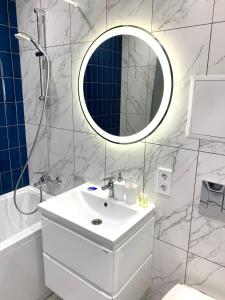 uma casa de banho branca com um lavatório e um espelho em Navy city center apartment двокімнатні апартаменти в центрі міста em Poltava