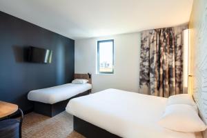 a hotel room with two beds and a tv at B&B HOTEL Paris Porte de Bagnolet in Bagnolet