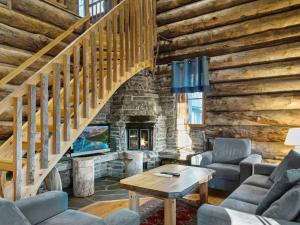 a living room with a staircase and a stone fireplace at Holiday Home Luostakka small by Interhome in Ylläsjärvi