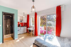 a bedroom with a bed and a kitchen with red curtains at SMILE APPARTS - Appartements - Au coeur de Lorient - Au calme - Tout Confort in Lorient