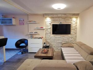 a living room with a couch and a tv on a brick wall at *** Apartment "IN" Zagreb in Zagreb