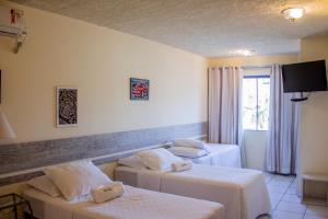 a hotel room with two beds and a window at Pousada Oma Helga in Pomerode
