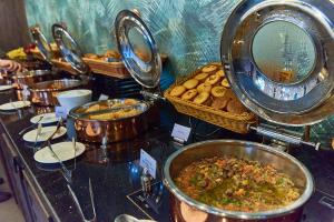 un buffet con muchas ollas de comida y pan en Rose Park Hotel - Al Barsha, Opposite Metro Station, en Dubái