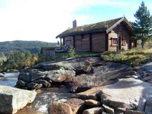 una cabaña de madera en una colina junto a un río en Holiday Home Kvila - SOW085 by Interhome, en Øyuvstad