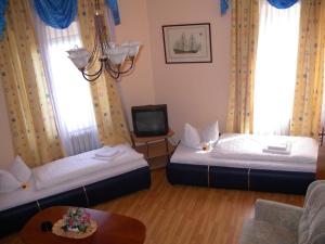 a room with two beds and a tv and a table at Hotel garni Djaran in Offenbach