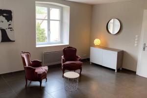 una sala de espera con 2 sillas y un espejo en LE MOULIN DE GRESSWILLER, en Gresswiller
