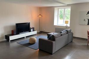 sala de estar con sofá y TV de pantalla plana en LE MOULIN DE GRESSWILLER, en Gresswiller
