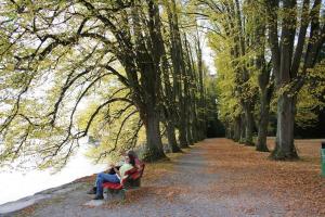 zwei Menschen sitzen auf einer Bank in einem Park in der Unterkunft Ferienhof Schöngarten in Lindau