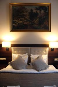 Una cama con dos almohadas y un cuadro encima. en Rembrandt Aparthotel, en Cracovia