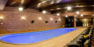 a large swimming pool in a building with a tile wall at Conacul Benke in Moacşa