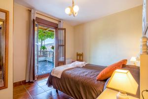 a bedroom with a bed and a door to a balcony at Alojamiento Los Pradillos in Capileira