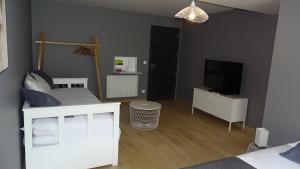 a bedroom with a white bed and a television at Chambres d'Hôtes Nature et bois BED AND BREAKFAST in Saint-Germain-sur-Morin