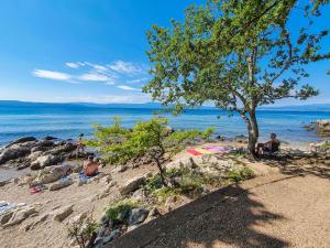 a group of people sitting on a beach near the water at Holiday Home Natali by Interhome in Njivice