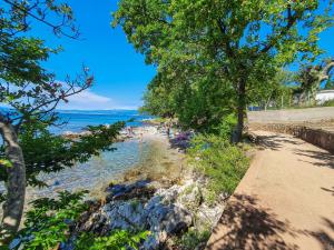 a beach with trees and people swimming in the water at Holiday Home Natali by Interhome in Njivice