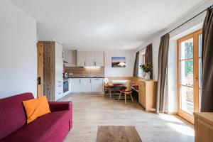 a living room with a purple couch and a kitchen at Haubenthal in Villabassa