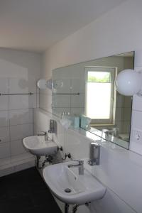 a white bathroom with two sinks and a mirror at Wohnen am Schloss, Herzog in Sondershausen