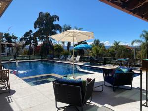 a swimming pool with chairs and an umbrella at Fazenda Pedra Lisa Hotel Boutique in Brumadinho