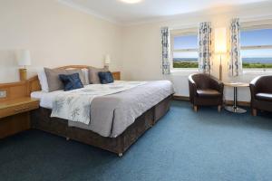 a bedroom with a large bed and two windows at Woodland Bay Hotel in Girvan
