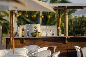 um bar com cadeiras brancas e garrafas numa mesa em Pousada Chez Toi em Jericoacoara