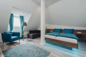 a bedroom with a bed and a blue chair at Hotel & Restaurant Hessischer Hof in Hainburg