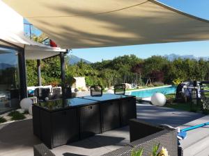 a covered patio with a table and a swimming pool at Chambres, cuisine, piscine, spa, billards, airhockey, nature in Fillinges