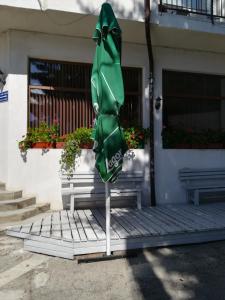 a green umbrella sitting in front of a building at Guest House Edelweiss in Govedartsi
