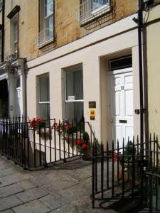 een huis met een witte deur en rode bloemen bij Brocks in Bath